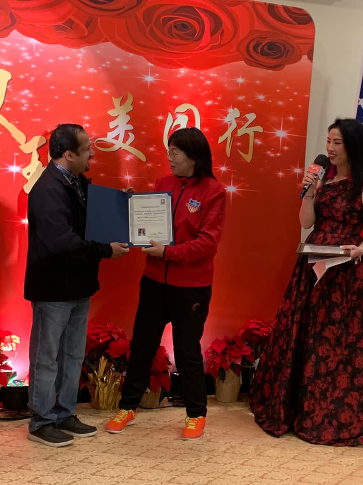 Satheesh Madhathil presenting a commendation at a community event