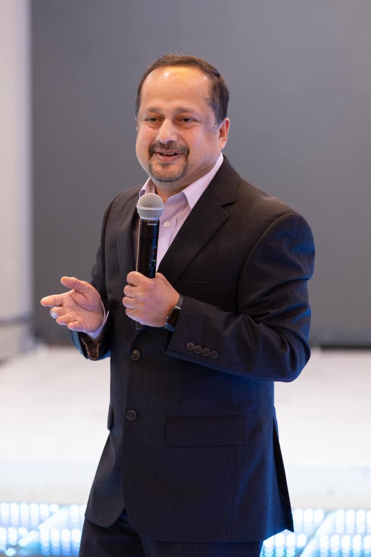 Satheesh Madhathil speaking to an audience with a microphone