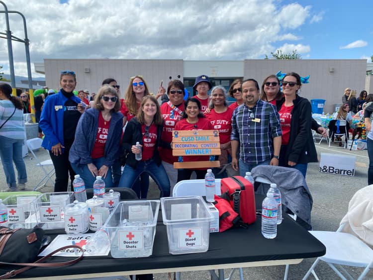 Satheesh Madhathil with staff and volunteers holding a CUSD table decorating contest winner sign